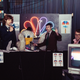 The party was broadcast live on YouTube by comedians in the Special Features improv troupe, who re-created a cringe-y four hour broadcast of the fair’s opening day. Josh Shreve annotated like a reporter breaking down amid chaos as Scott Anderson held a microphone up to the party’s mascot, “Seymore D. Icks,” a mockery of the fair’s fluffy pelican avatar Seymore D. Fair. Nearby, Sam Moody took a break from anchor duty to laugh at the feed on a live monitor. Photo: Akasha Rabut.